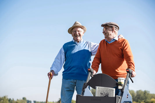 Two senior men walking with a Camino smart walker talking and laughing