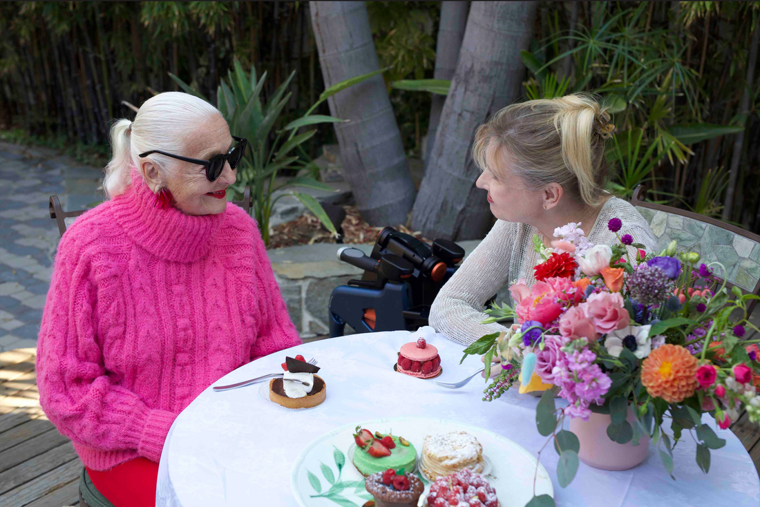 Lady Jane in a gorgeous pink roll neck jumper and her daughter eating cake at the garden table